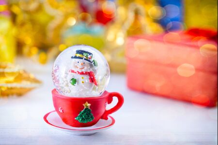 Colorful Merry Christmas background. Snowball with Snowman inside, snow flake is falling down. New year Gifts and decoration. Vintage postcard. Space for text. Selective focusの写真素材