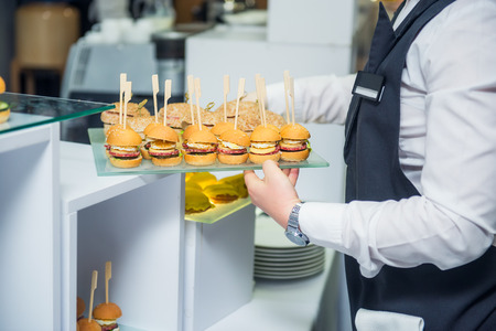 The waiter is servering catering buffet table with food and snacks for guests of the event. Dining...