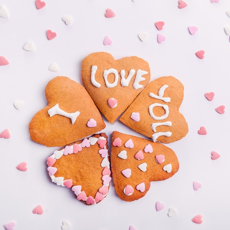 Homemade cookies in the shape of heart with letteing I Love You with sweets sugar candy hearts on...