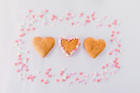 Homemade cookies in the form of hearts in the frame of sugar candy hearts decor on the white background. Valentine day concept. Gift for lover. Selective focus. Space for textの写真素材