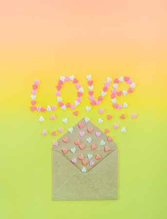 Sweets sugar candy hearts fly out of craft paper envelope and create word Love on the bright gradient background . Valentine day. love diversity concept. Gift, message for lover. Space for textの写真素材