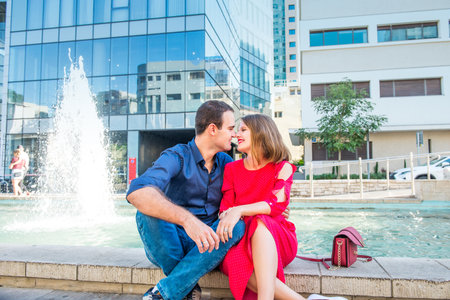 Romantic couple sitting on the bench near the city fountain and enjoying moments of happiness. Love, dating, romance. Lifestyle and tourism concepts. Selective focus. Copy spaceのeditorial素材