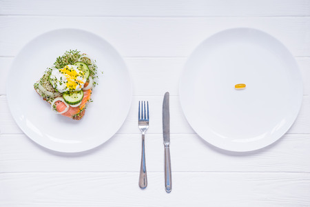 Concept of choice - healthy food or medical pills, top view on the white plate and wooden table....