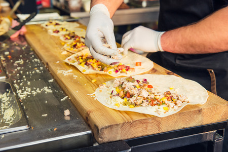 Chef's hands preparing mexican tacos at a street food market, festival, event. Process cooking. Street food concept. Selective focus. copy spaceの写真素材