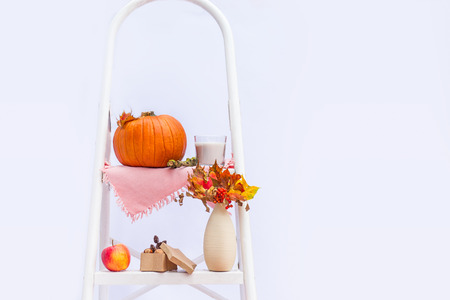 Cosy composition with natural decor of pumpkins, candles, fall leaves in vase, cones and nuts on the steps of rung ladder on white background isolated. Autumn holiday, harvest concept. Copy spaceの写真素材