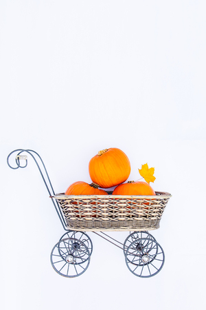 Top view Vintage Garden carriage basket with ripe pumpkins on the white background isolated . Autumn harvest, thanksgiving, halloween concept. healthy diet food. Flatlay. Selective focus. Copy spaceの写真素材