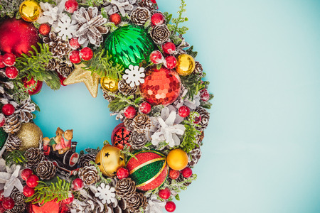 Top view Beautiful traditional bright Christmas wreath decorated with pine cones, spruce branches,berries, balls, stars, decorative beers on blue background isolated. Close up, flat lay. Copy space.の写真素材