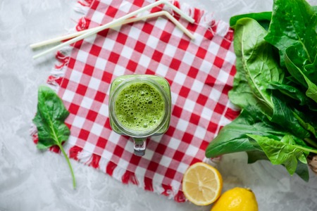 Top view Healthy green spinach smoothie in a jar mug with ingredients on the checkered napkin on the white marble table. Selective focusの写真素材
