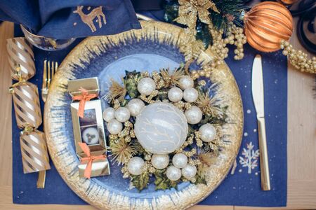 Top view Christmastime table setting, festive dinnerware decorated with details and balls in Blue...