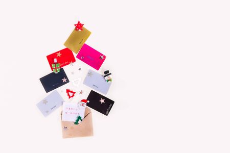Colorful store gift cards, decor and greeting Merry X-mas card with envelope in shape of Christmas tree on white background. Flat lay. New year ideas for presents. Holiday sale mock up with copy space.の写真素材