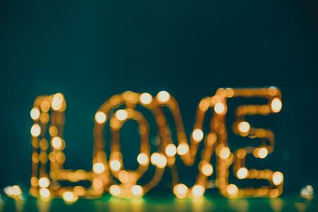 Blurred and lighting word Love on dark green background. Valentine day card. Bright festive ideas. Copy spaceの写真素材