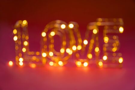 Blurred and lighting word Love on dark red background. Valentine day card. Bright festive ideas. Copy spaceの写真素材