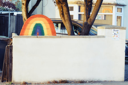 Poole, United Kingdom - April 23, 2020: Rainbow shape made of wood standing on private fence wall made by children. Message of hope and support. Coronavirus covid-19 virus outbreak. Copy spaceのeditorial素材