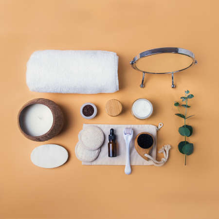 Top view home self-care kit for face. Dry lymphatic drainage massage brush, mezoroller, loofah pads, natural serum, scrab, cream, towel on beige background. DIY natural eco cosmetics and home spa.の写真素材
