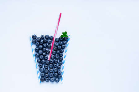Creative layout of blueberry smoothie glass made with cocktail straws on a white background...