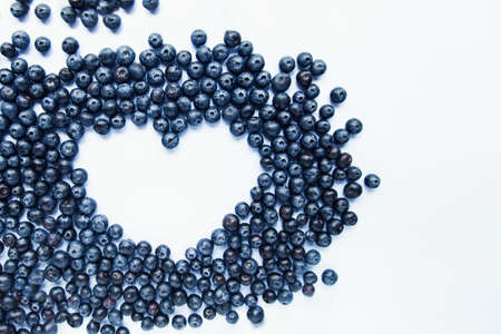 Heart shape made of fresh Blueberries on white background. Healthy food, summer berries. Minimal...