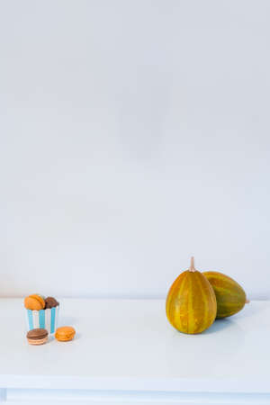 Macarons dessert in a paper cup, and decorative pumpkins on  whiteの写真素材