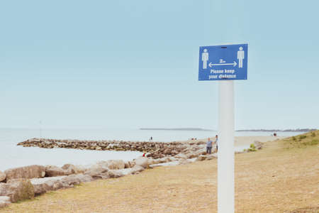 Message with Please keep your distance on the sign standing on the beach. New normal social distancing measures in public places during a Covid-19 pandemic. Outdoor area. Copy space.の写真素材