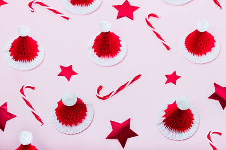 Creative minimal christmas pattern background. Christmas candy canes, red stars and paper santa caps...