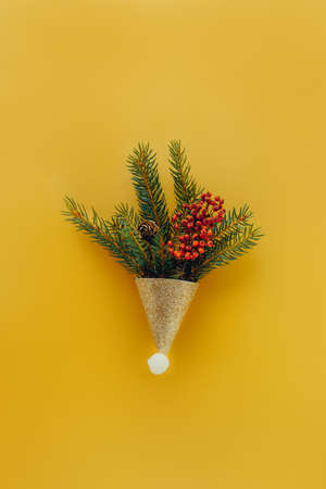 Festive Christmas composition in decorative shining golden cap with spruce branches and dry berries...