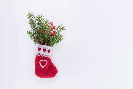 Christmas decorative handmade felt sock with spruce branches and dry berries and cone on white. Festive composition with natural decor. Eco friendly, zero waste Christmas background with copy spaceの写真素材