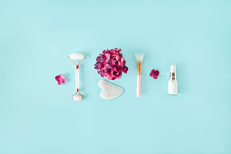 Top view composition with pink jade roller face massager, gouache scraper, brush, natural serum and...