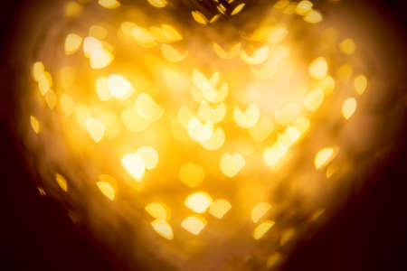 Close up defocused heart shape frame with golden bokeh background inside. Valentines day card. Copy...