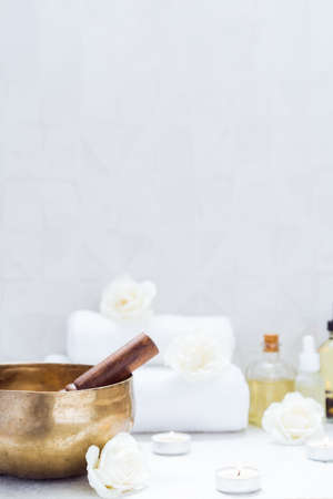 Spa and wellness massage setting with Tibetan singing bowl. Asian relaxing spa procedure with essential oils and sound healing therapy. Alternative medicine and body care. Vertical card. copy space.の写真素材