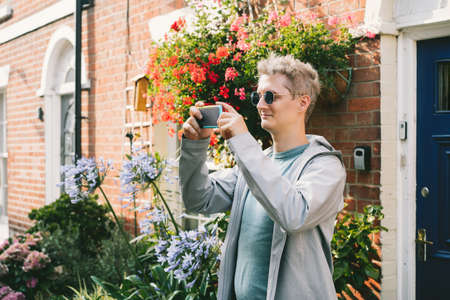 Young male tourist filming video or taking photo pictures on mobile phone during walking in the...
