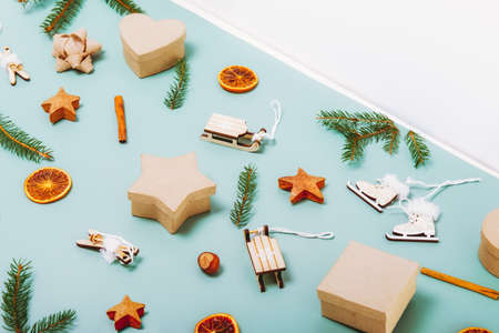 Christmas side view green background with fir branches, eco friendly cardboard gift boxes, wooden toys, cinnamon, dried oranges and white triangle copy space. Zero-waste, no plastic gift packaging.の写真素材