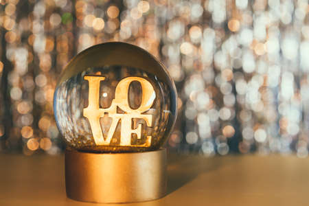 Valentines day background. Glitter globe with word LOVE on the golden shining bokeh background. Selective focus. Copy space.の写真素材