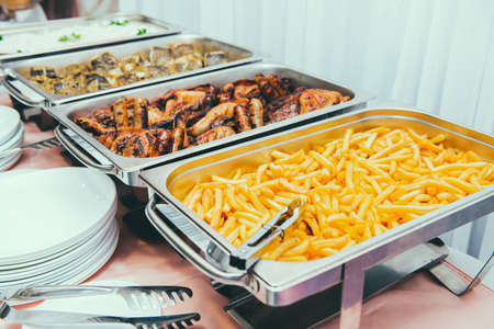 Cuisine Culinary Buffet Dinner Dining Food Celebration Party Concept. Trays with main meals - french fries chips, rice, meet and fish. Service at business meeting, weddings. Selective focus.の写真素材