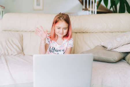 Kids using technology. Happy girl having good time using laptop, watching video, talking online on...