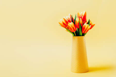 Colorful fresh spring tulips flowers in vase on light yellow background. Spring, womans day, 8...