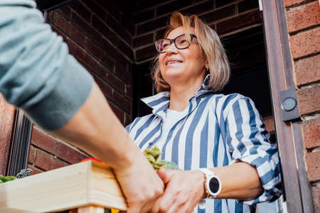 Home fresh food delivery. Woman taking wooden box with vegetables and fruits. Support local farmer food production . New Start of a healthy life, weight loss concept. Online food order. Recipe boxの写真素材