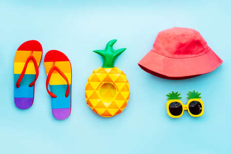 Top view summer beach, pool vacation concept with rainbow color flip flops, pineapple inflatable...