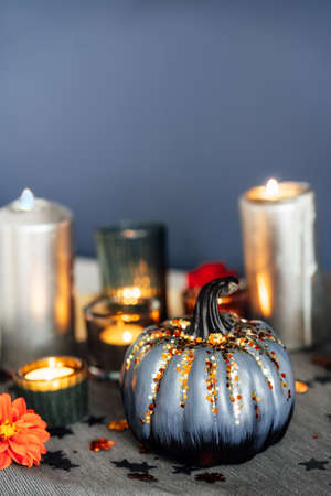 Autumn cozy mood composition for home decoration. Gray pumpkin with sequins, burning candles, fresh dahlia flowers on tray with napkin. Fall, hygge home decor. Vertical. Selective focus. Copy space.の写真素材
