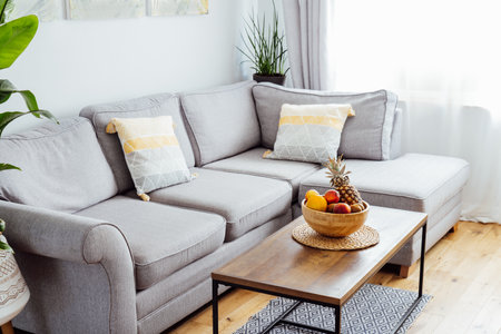 Stylish and modern scandinavian interior of open space living room with bamboo bowl with fruits on...