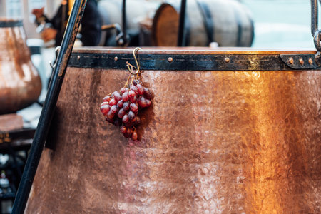 Bunch of grapes hanging on the pot of mulled wine in a stall in a Christmas market. Close Up of...