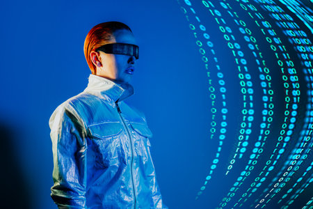 Woman, dressed in futuristic holographic clothes and eyeglasses with reflection of matrix code and matrix digital numbers artificial intelligence before her in blue light. Selective focus.の写真素材