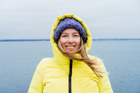 Portrait of happy smiling woman in warm clothes with blown hair enjoying the moment during a walk on...