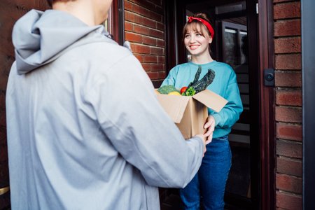 Home fresh food delivery. Woman taking cardboard box with vegetables and fruits. Support local farmer food production. New Start of a healthy life, weight loss concept. Online food order. Recipe boxの写真素材