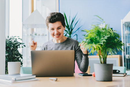 Excited happy middle aged neutral gender woman feeling winner rejoicing online win got new job opportunity, overjoyed motivated girl doing yes gesture, receive good results on pc celebrating admissionの写真素材