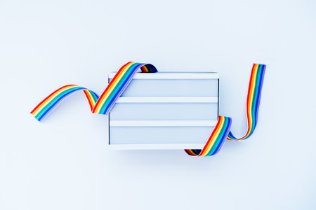 Top view White light box mockup with rainbow LGBT ribbon on a light background isolated. Copy space...