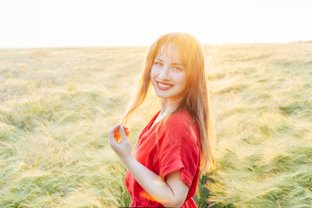 Young happy woman in red dress walking in wheat field on sunset. Breathe of freedom. Positive emotions feeling life, peace of mind. Mental health practice. Nature relaxation. Soft selective focusの写真素材