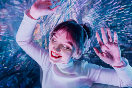 happy smiling woman with closed eyes and raised hands in white clothes and headphones dancing. Music...