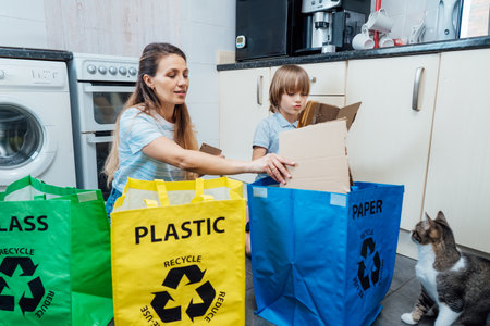 Mother is teaching kid how to recycle help the boy aware environmental importance - mom educates son sort garbage into different bins on kitchen. Family sorting garbage at home. Concept of recycling.の写真素材