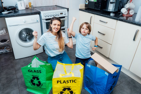 Happy funny mother and son after sorting garbage at home kitchen. Mother is teaching kid how to recycle help the boy aware environmental importance. Concept of recycling. Selective focus.の写真素材