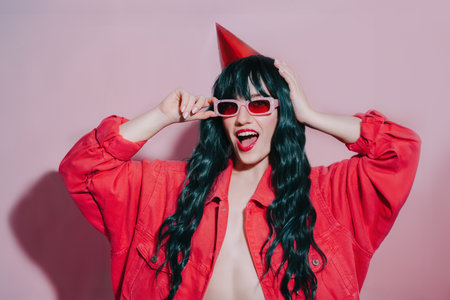 Celebration and party. Having fun. Cheeky bright fashion girl with birthday cap on dark green long...