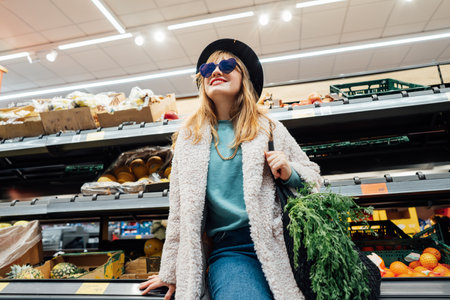 Portrait of Stylish fashion smiling woman in the supermarket store during selecting fresh products. Healthy eating diet, go vegan. Grocery Shopping. Veganuary diet month. Selective focusの写真素材